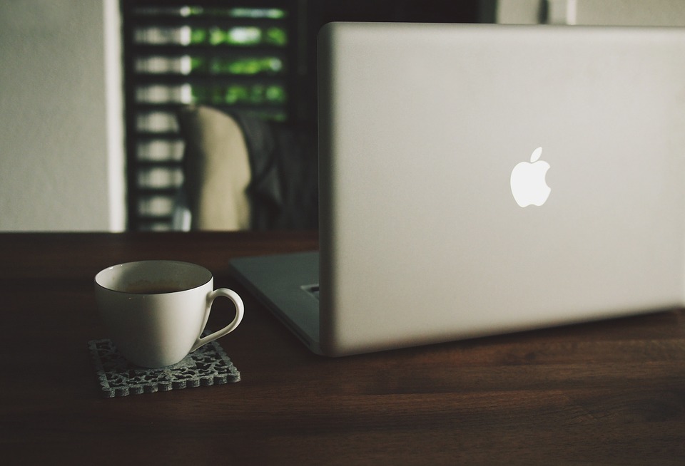 macbook next to a coffee mug on a fancy wooden table